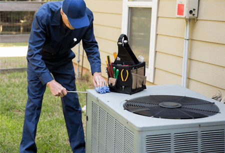 Figure 1: Maintenance staff works on an exterior unit of a central air conditioner.