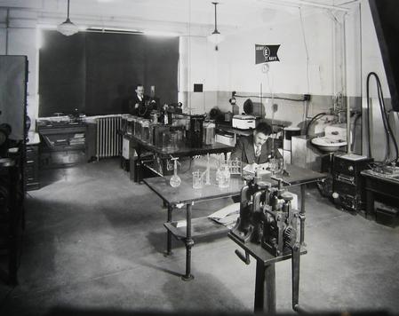 In the early days of Indium Corporation, technologists work in a lab with the U.S. Army/Navy 