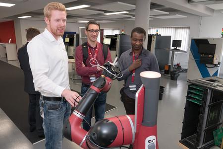 Georg Walz, who is writing an undergraduate thesis at Viscom, shows Sawyer working at an inspection system to guests at the Viscom Technology Forum 2018 in Hanover, Germany.